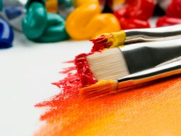 three silver paint brushes on white textile