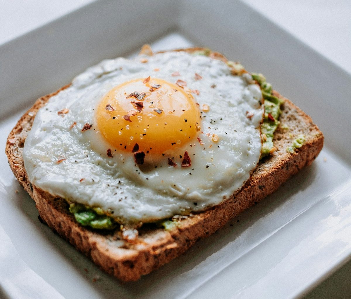 bread with sunny side-up egg served on white ceramic plate