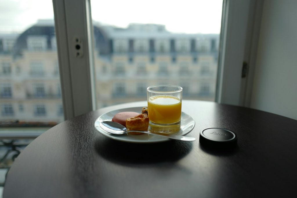 cup filled with yellow liquid beside bread on plate