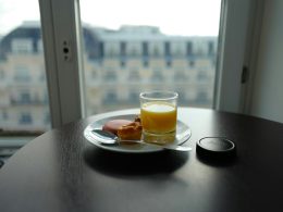 cup filled with yellow liquid beside bread on plate