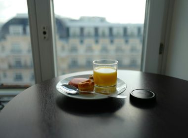 cup filled with yellow liquid beside bread on plate